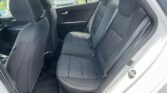 Rear seat area of a car with dark gray patterned fabric seats and visible seat belts, door panel on the left, and open rear door.