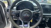 Driver’s view from inside a Kia: steering wheel centered with gauge cluster behind and the infotainment touchscreen to the right.