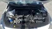 Open hood of a Kia showing the engine bay and battery visible beneath the windshield wipers.