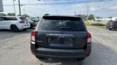 Rear view of a black Jeep SUV in a parking lot with other vehicles and overhead power lines in a sunny day scene