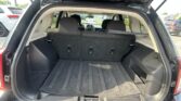 Open car trunk in an SUV, exposing a large empty cargo area with rear seats upright and dark carpeting.