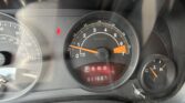 Close-up of the car dashboard showing tachometer, speedometer, gear indicator (PRND), and a red seatbelt warning light.
