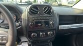 Driver's-seat view of the car interior: steering wheel, center dashboard with dual round air vents, radio, climate controls, and gear shifter.