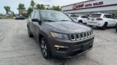 Front view of a gray Jeep SUV parked in a lot in front of the EZ Loan Auto Sales storefront with a red sign above the building.