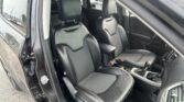 Front interior of a car showing black leather seats with stitched seams and honeycomb center panels, driver and passenger seats visible, gear shifter and center console in view.
