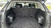 Open SUV trunk with rear seats upright and empty cargo area, car lot visible behind.