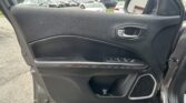 Close-up of a car's driver-side door interior with window controls and chrome handle; parking lot visible outside the window.