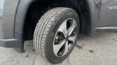 Close-up of a vehicle's front wheel and tire inside the wheel well, with water droplets on the fender and rim visible.