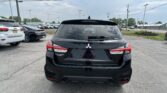 Rear view of a black Mitsubishi Outlander Sport parked in a lot, other cars nearby, power lines overhead and a cloudy sky.