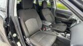 Front interior of a car with two black fabric seats and headrests, open driver door showing door frame and seat belts.