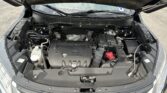 Under-hood view of a car engine bay with the MIVEC engine cover visible and various hoses and wires.