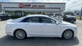 White luxury sedan parked in front of a car dealership with an E-Z LOAN Auto Sales sign and glass storefronts behind it.