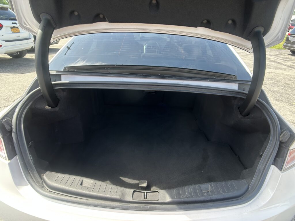 Open trunk of a sedan showing empty black cargo space and rear window view