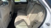 Rear passenger area of a beige leather SUV with captain-style second-row seat and tan door panels, showing seat belts and ample legroom.