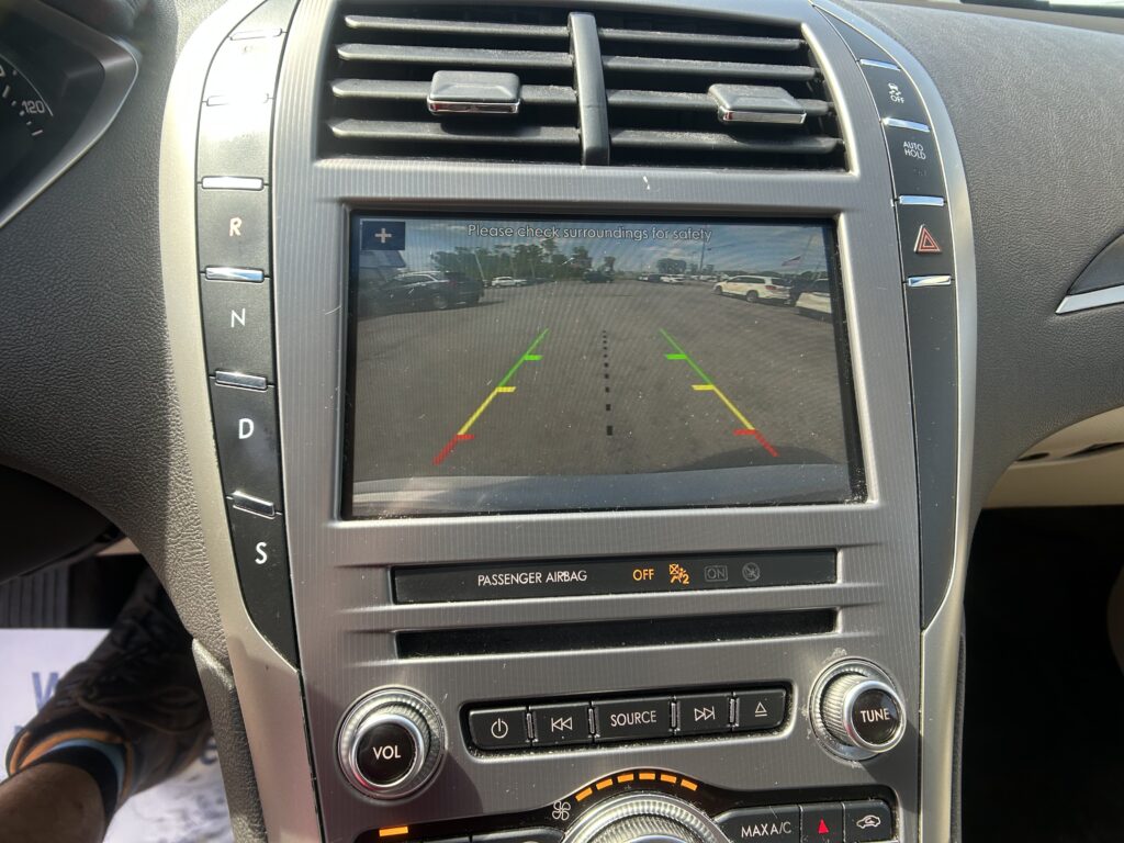 Car's infotainment screen displaying the rearview camera with green/yellow/red guide lines for parking.