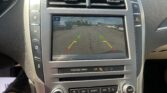 Car's infotainment screen displaying the rearview camera with green/yellow/red guide lines for parking.