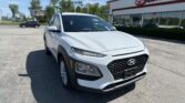 White Hyundai SUV parked in front of an EZ LOAN AUTO dealership on a sunny day, close-up view of the front end.