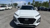 Front view of a white Hyundai SUV in a crowded parking lot on a sunny day, other cars nearby and blue sky above.