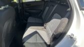 Rear interior of a car with black-and-gray fabric seats, headrests, and three seat belts visible; parking lot outside the windows