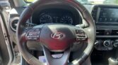 Driver's cockpit view with steering wheel in foreground, dashboard gauges, and central touchscreen display on the right in a Hyundai interior.