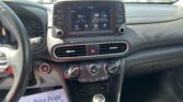 Car dashboard view: center touchscreen radio shows 93.7 FM with vehicle controls around it and gear lever in foreground.
