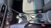 Close-up of a car interior: front seat with houndstooth-pattern upholstery, gear shifter, climate controls, and cup holder visible in the center console