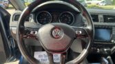 View from the driver's seat showing a Volkswagen steering wheel with the instrument cluster and center console in view, sunlight through the windshield.