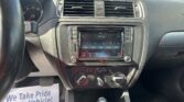 Car dashboard interior with a center touchscreen, two air vents, and climate controls; a flyer on the floor reads 'We Take Pride In Your Vehicle'.
