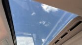 Open car sunroof showing blue sky with white clouds from inside the vehicle