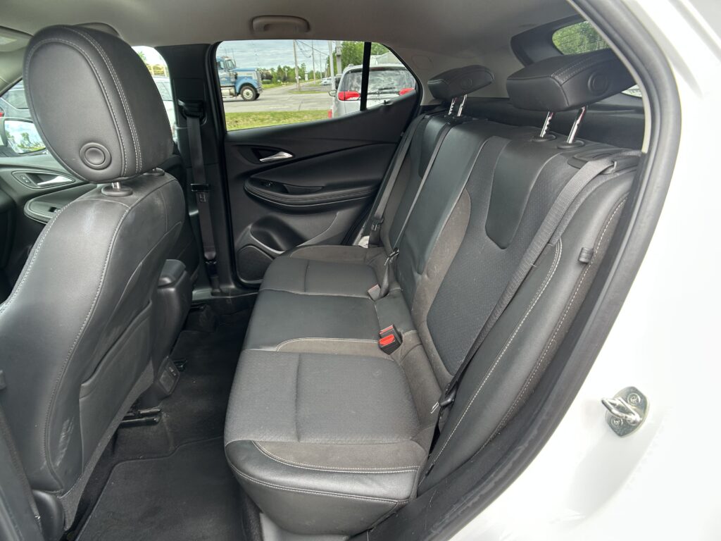 Rear passenger seats in a car with black upholstery, visible seat belts and headrests.