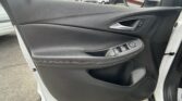 Interior car door panel with silver door handle and power window controls visible, parked lot outside window.