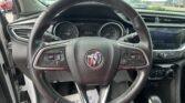 Close-up of a Buick steering wheel from the driver’s perspective, with the instrument cluster and infotainment screen visible in the dash.