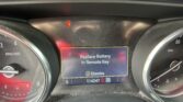 Close-up of a car dashboard: center screen shows 'Replace Battery In Remote Key' with a red warning light above, surrounded by gauges and dust.
