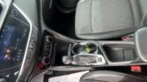 Interior of a car showing the center console, touchscreen display, gear shifter, and front seats from a driver’s perspective.