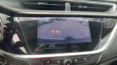 In-car center console: tablet-style backup camera display with parking guide lines, flanked by air vents and a hazard button to the right.