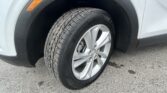 Close-up of a car tire and alloy wheel on a light-colored SUV, with the fender and an orange side marker nearby.