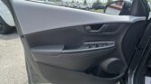Front passenger door interior with window controls, armrest, and speaker in a parked car.