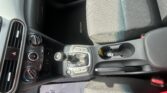 Interior of a car showing center console with gear shift, climate controls, and a patterned front passenger seat labeled 'KONA'