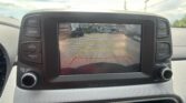 Rearview camera screen showing a parking lot with colored guide lines behind the car and the safety message text visible at top.