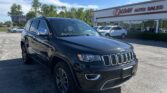 Black Jeep SUV parked in front of a car dealership on a sunny day, with the EZ Loan Auto Sales sign in view.