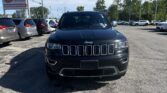 Front view of a dark Jeep SUV in a car dealership lot with rows of vehicles and an EZ Loan Auto Sales sign in the background