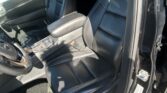 Interior of a black leather SUV with front captain's chairs, center console, and open driver’s door; parking lot visible outside.