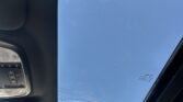 Open sunroof with blue sky visible from inside the car cabin, showing overhead console on the left.