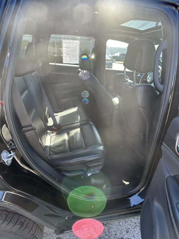 Interior view of a black leather SUV with sun glare and rainbow lens flares across the cabin.