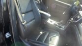 Black leather front seats inside a car with center console and sunroof, dealership lot visible outside the window.