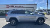 Silver SUV in foreground outside E-Z Loan Auto Sales storefront under a bright blue sky. A red-and-white sign reads 'E-Z LOAN AUTO SALES' with other cars and a Toyota dealership in the background.