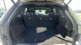 Open SUV tailgate revealing a spacious cargo area with folded third-row seats upright in a black interior