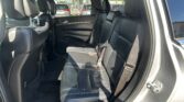 Back seat of a black-leather SUV with three seating positions and visible seat belts, view through the rear passenger door window to outside traffic