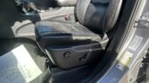 Interior of a car front seat area: black leather seats, center console with gear shifter, armrest, and seatbelt buckle visible on the right side of the driver’s seat.