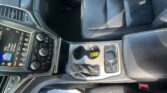 Inside a modern car: center console with touchscreen, climate controls, cup holders, and black leather seats.